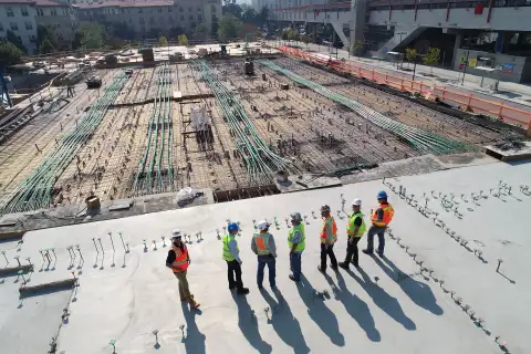 Seven construction workers looking at foundations of a new development