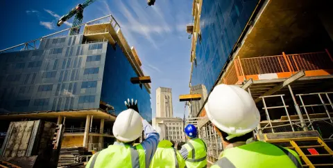 Construction workers looking at buildings in construction with cranes in the background