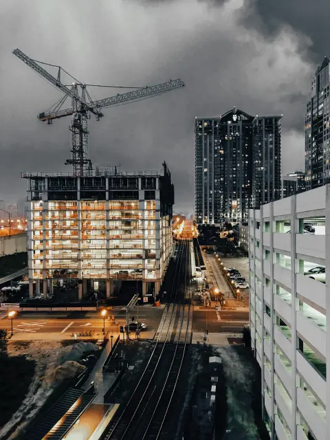 New building in city skyline with cranes lit up at night