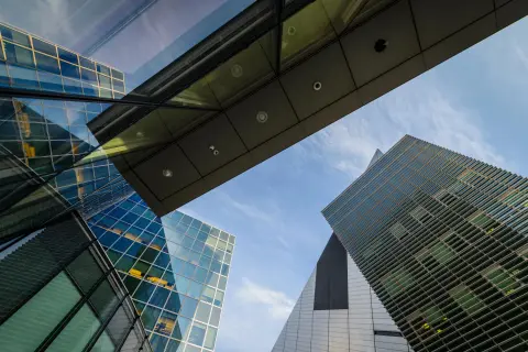 A worm's eye view of high-rise glass buildings under a blue sky.